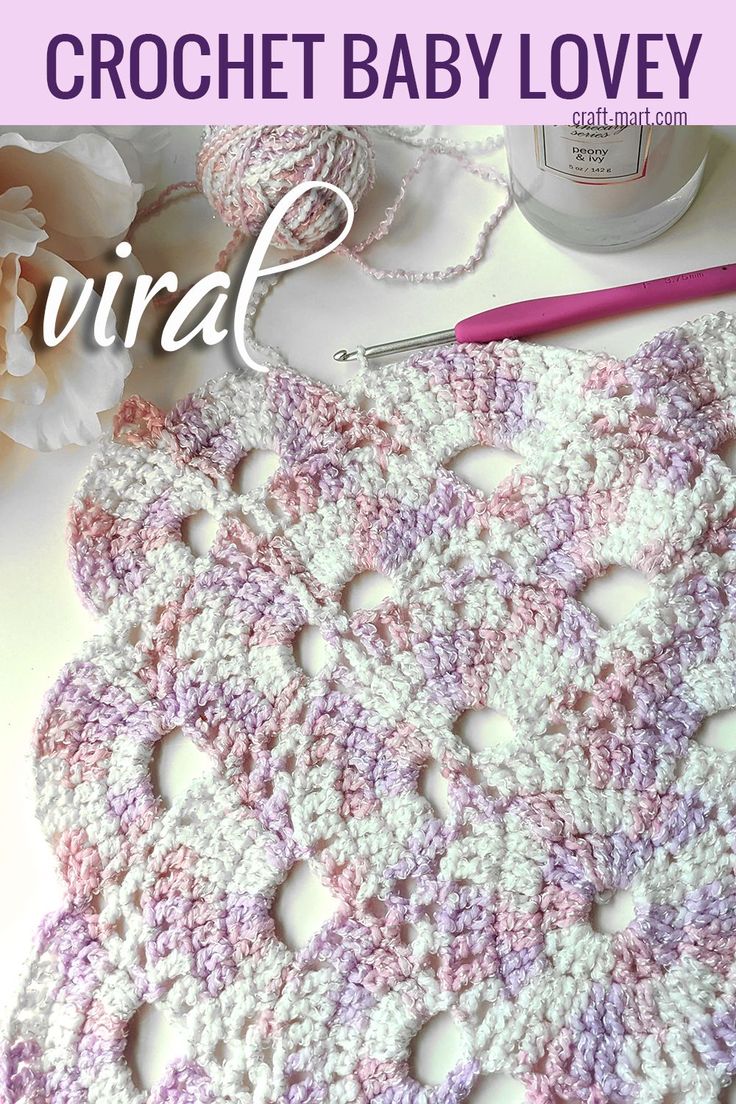 the crochet baby lovey is laying on top of a table next to flowers