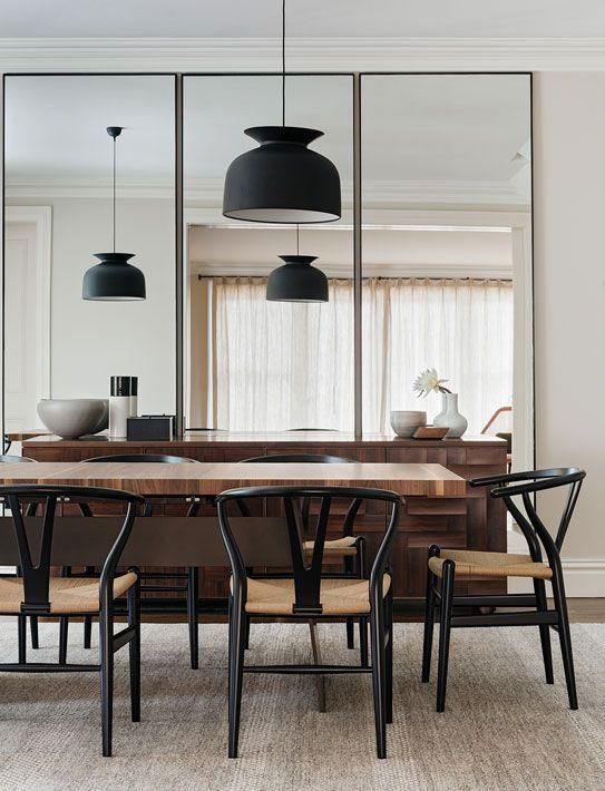 a dining room table with four chairs and a large mirror in the wall above it