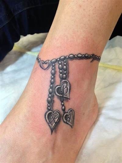 a woman's foot with a chain and hearts tattoo on it, which is attached to the ankle