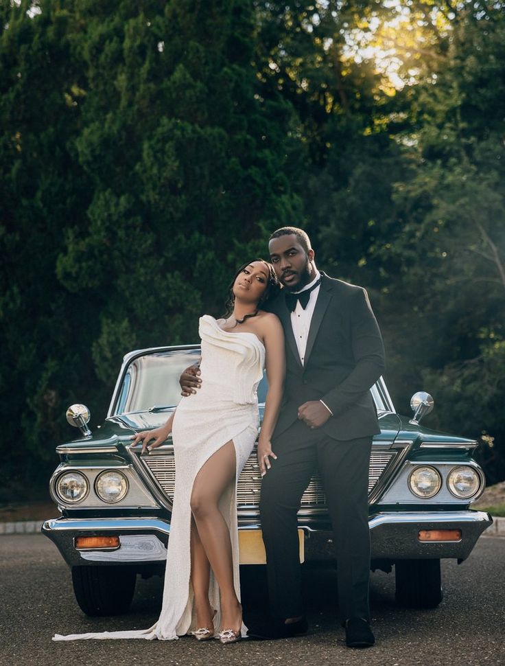 a man and woman standing next to an old car