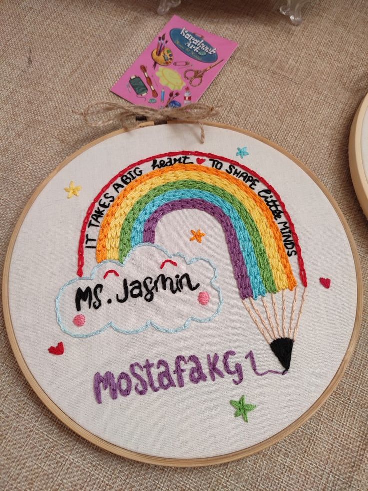 two embroidery hoops with the words ms jesmin and a rainbow