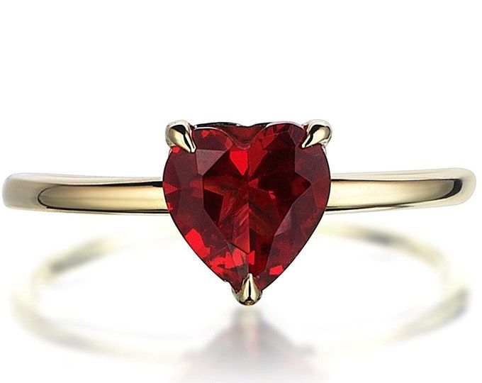 a heart shaped red stone ring on a white background