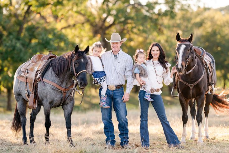 a man, woman and child standing next to two horses