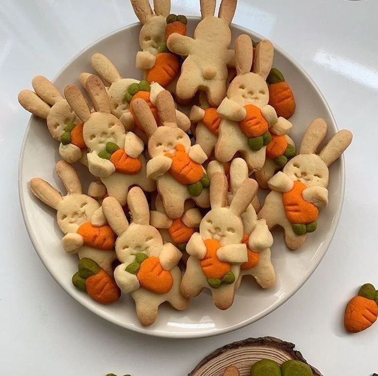 a white plate topped with cookies covered in bunny ears and carrots on top of a table