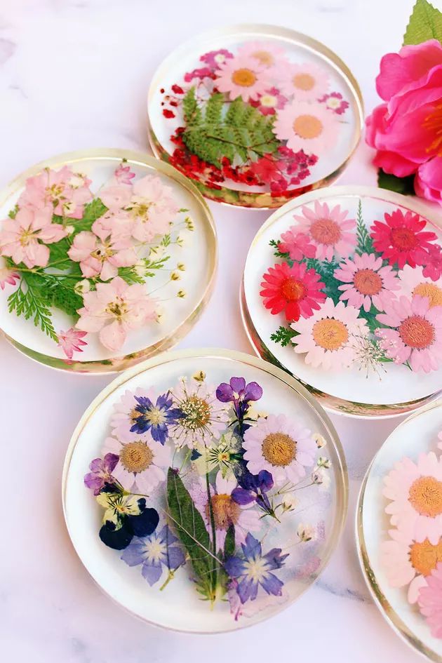 four plates with flowers painted on them are sitting on a marble countertop next to a pink flower bouquet