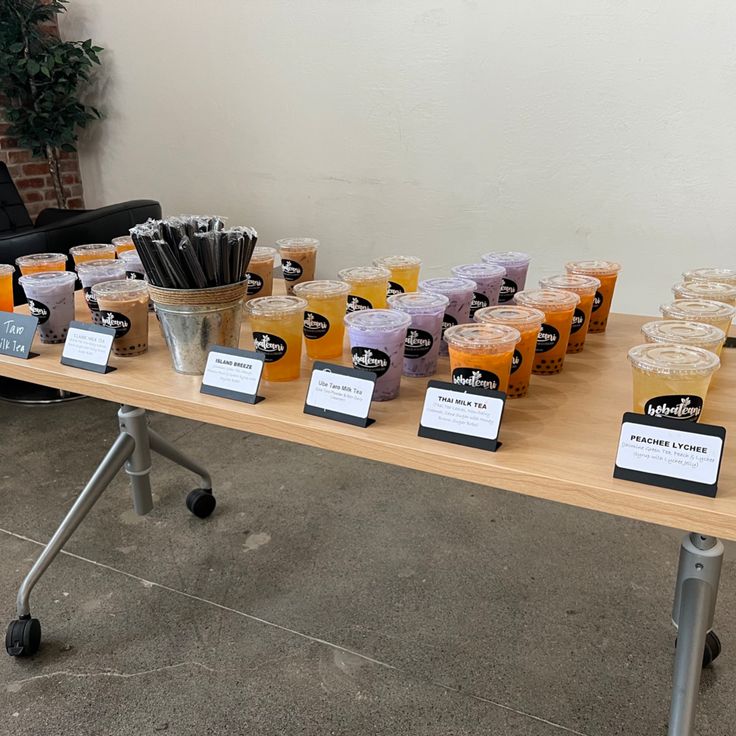 a table topped with lots of cups filled with oranges and drinks next to a black chair