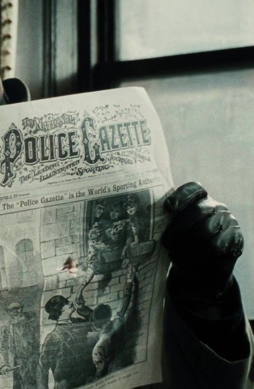 a person holding up a newspaper in front of their face with the word police gazette printed on it