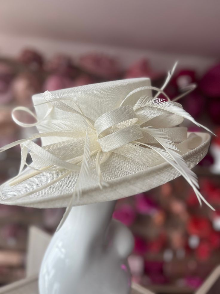 For wedding guests and the mother of the bride this classic cream ladies hat is our most popular hat for weddings, and it's easy to see why! Made with the finest abaca sinamay, this stunning cream wedding hat is stylish from every angle! Decorated with loops and feathers, the elegantly detailed trim provides movement and balance whilst creating volume without looking too heavy and the slightly upturned wide brim is a timeless classic design that will suit all ages and face shapes. These beautiful cream occasion hats are comfortable to wear with an adjustable sizing band, meaning one size fits all and a secure fit every time. From weddings and occasions to derby day and the races, this beautifully designed cream occasion hat will top your look with elegance and style whatever the event. Sty Cream Adjustable Hat For Wedding, Adjustable Cream Wedding Hat, White Wedding Hats, One Size Fits Most, Elegant Beige Wedding Hat, Cream Adjustable Sinamay Hat, Popular Hats, Church Lady Hats, Occasion Hats, Sinamay Hats