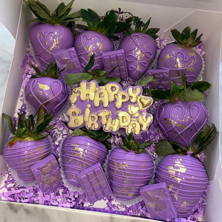 a box filled with purple chocolate covered strawberries and topped with happy birthday written on the top