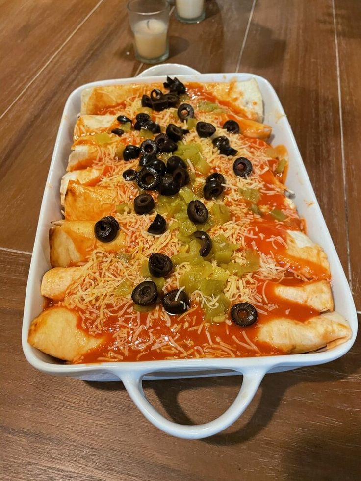 a casserole dish with olives, cheese and other toppings on it