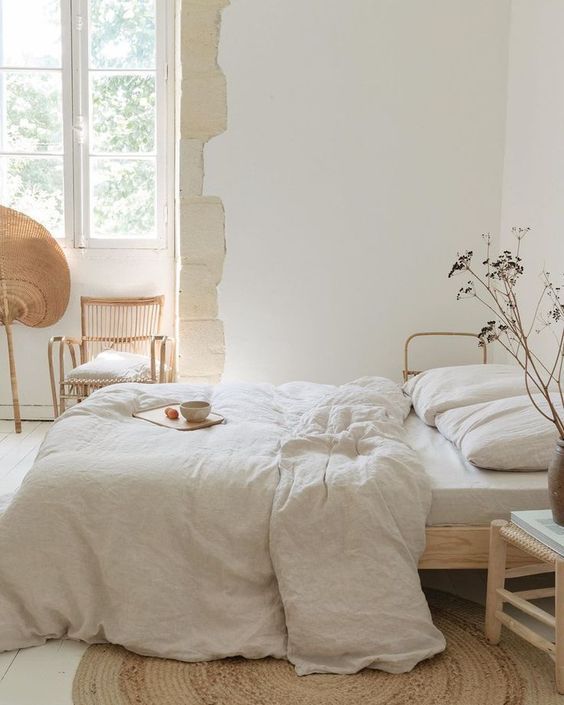 a bed with white sheets and pillows in a room