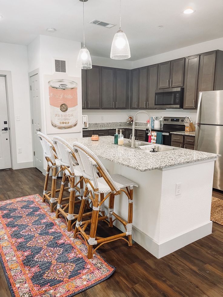 a kitchen with wooden floors and white counter tops next to an area rug on the floor