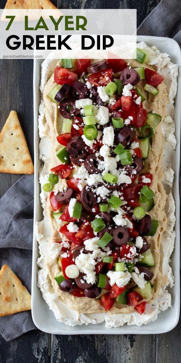 a platter filled with greek dip and pita chips on top of a wooden table