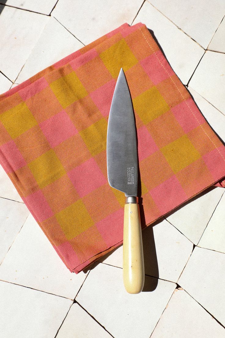 a large knife sitting on top of a pink and yellow cloth