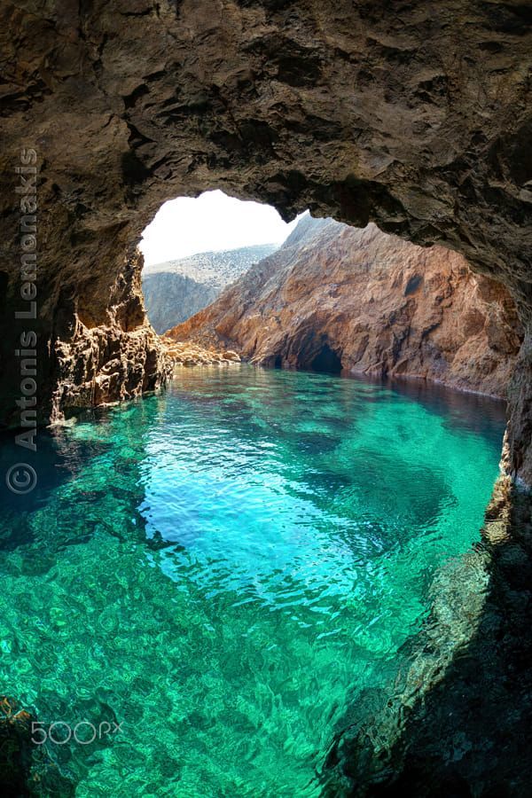 the water is crystal blue and clear in this cave entrance, with green algae growing on the floor