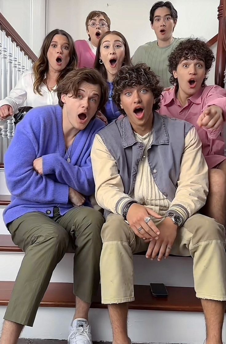 a group of young people sitting on top of a wooden bench with their mouths open