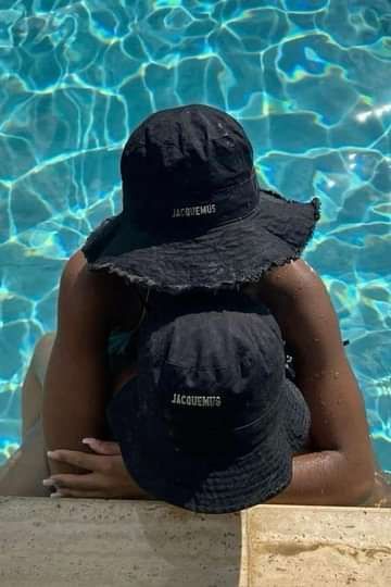 two people sitting in front of a swimming pool wearing hats with names on them,