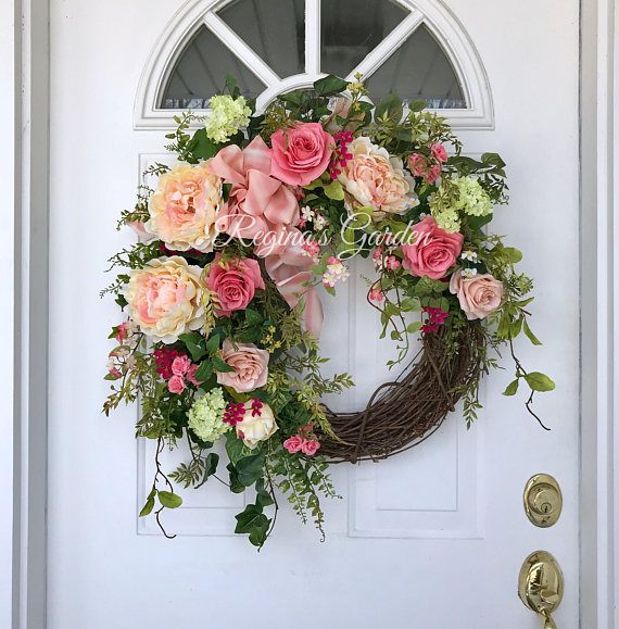 a wreath with pink and white flowers is hanging on the door to a front door