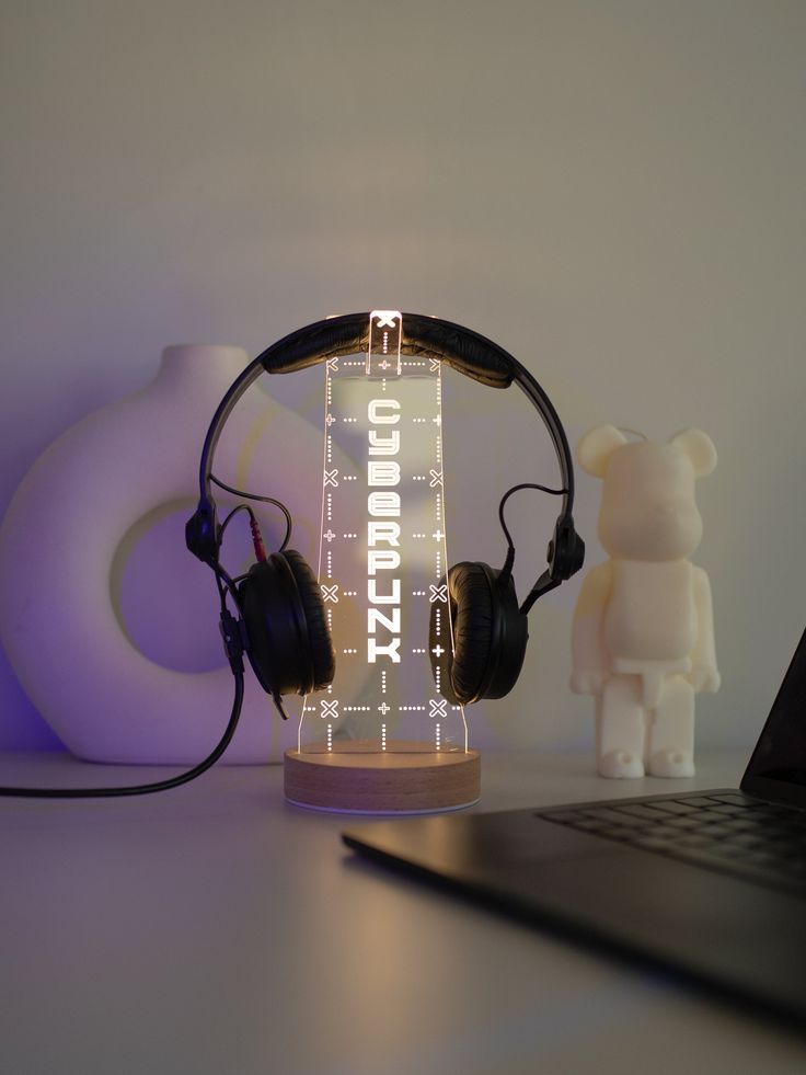 a laptop computer sitting on top of a desk next to headphones and a teddy bear