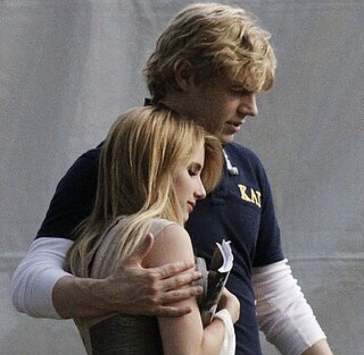 a man and woman hugging each other in front of a wall