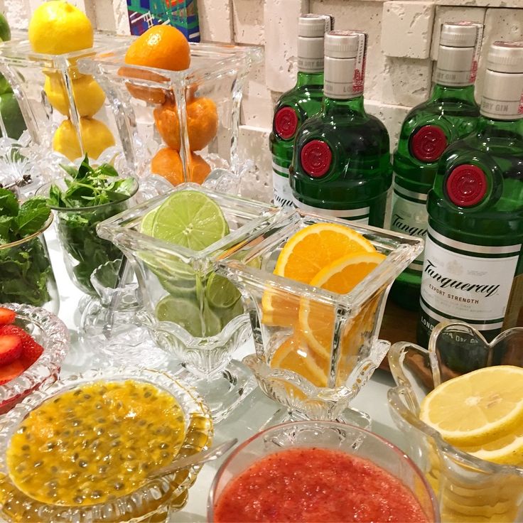 various fruits and vegetables are arranged on a table with bottles of alcohol in the background