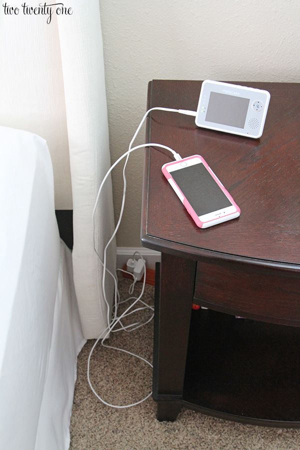 a cell phone is plugged into an outlet on a nightstand