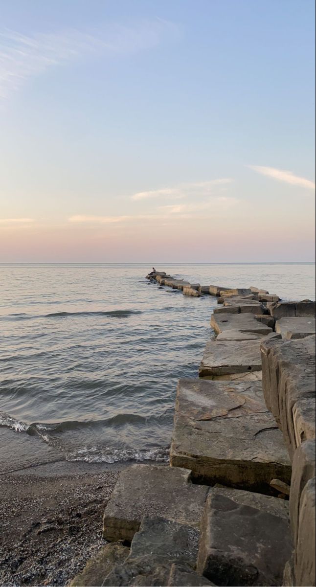 a long stone wall stretches out into the ocean