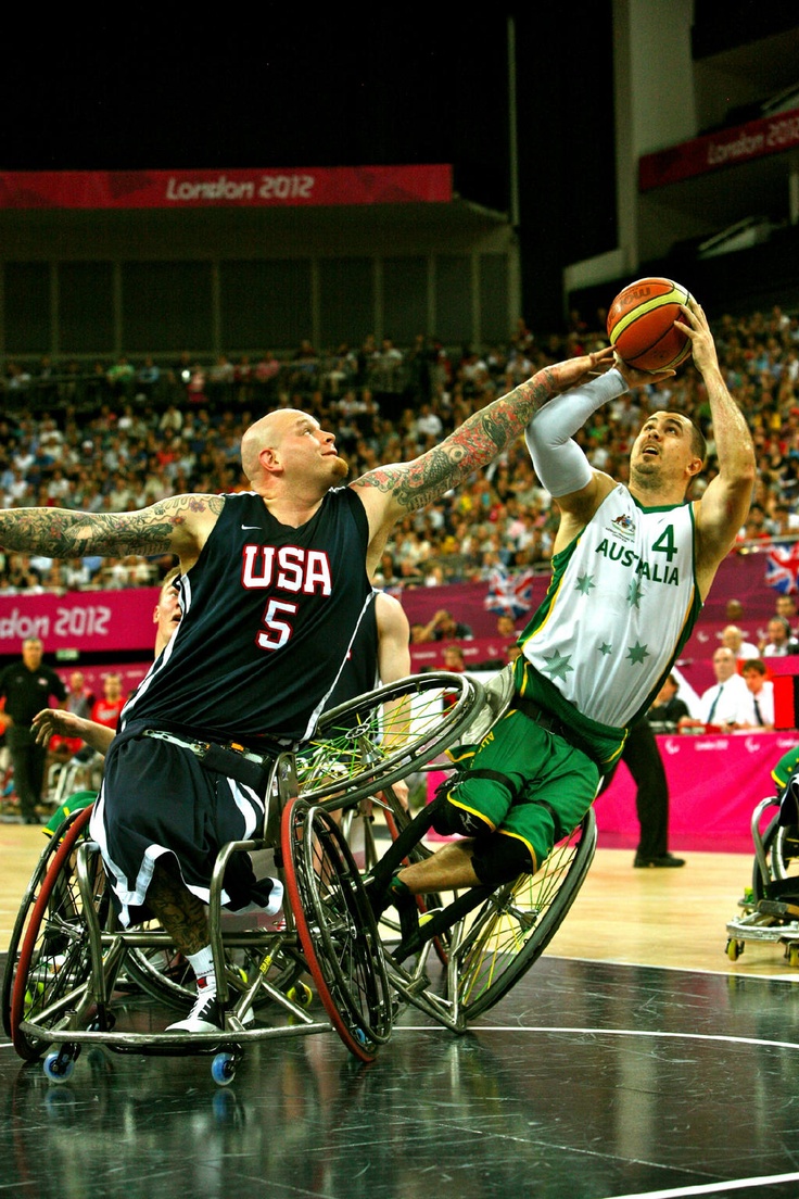 two men in wheelchairs playing basketball on a court