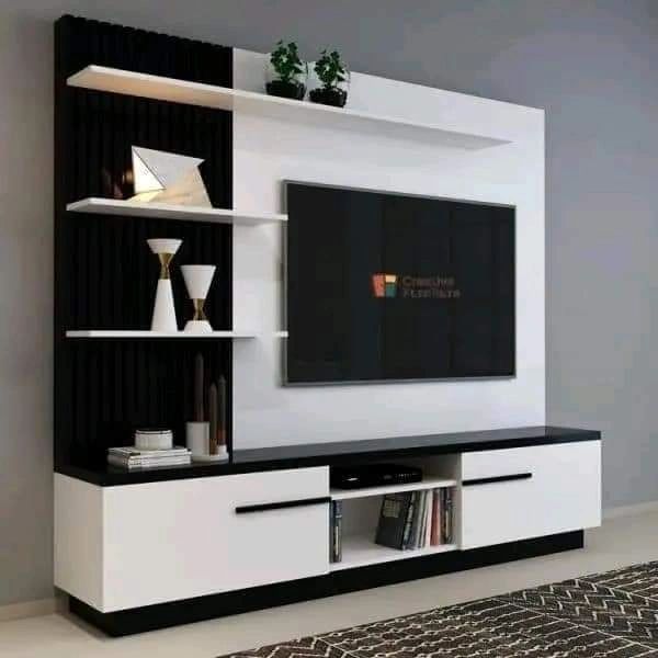 a white and black entertainment center with bookshelves on each side, television mounted to the wall