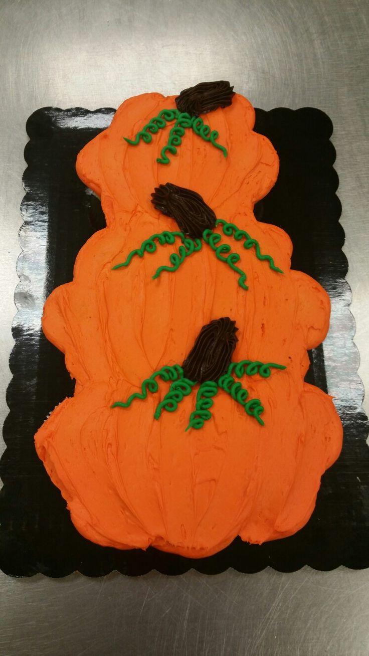 two decorated cakes sitting on top of a black plate in the shape of three pumpkins