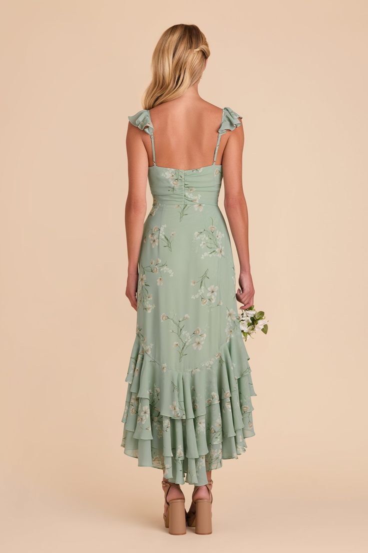 the back of a woman wearing a green dress with floral print on it and straps