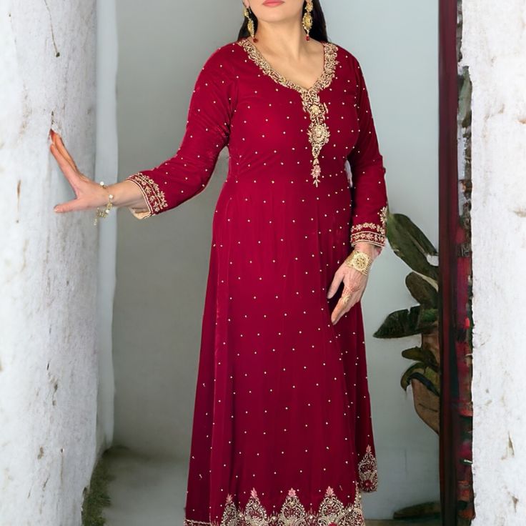 Elevate Your Ensemble With Our Regal Elegance Red Velvet Two-Piece Suit Set, A Captivating Combination Of Luxury And Sophistication. The Eye-Catching Shirt Is Adorned With Exquisite Nakshi Dabka Work, Intricately Woven To Perfection, And Embellished With Pearls Cascading Across The Full Length, Creating A Truly Mesmerizing Effect. Paired With A Plush Velvet Trouser, This Ensemble Exudes Regal Charm And Refined Elegance. Make A Statement Of Timeless Sophistication With This Stunning Suit Set, Per Red V-neck Dress With Dupatta, Fitted V-neck Dress With Zari Work, Fitted Red Salwar Kameez With Dabka Work, Elegant Red Long Sleeve Sets, Fitted Red Anarkali Set With Dabka Work, Elegant Red Salwar Kameez With Dabka, Red Floor-length Dress With Dabka Work, Red Floor-length Dresses With Dabka Work, Red Long Sleeve Salwar Kameez For Party