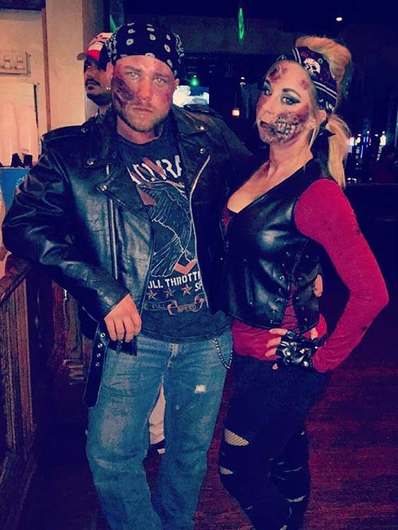 a man and woman dressed up as zombies pose for a photo in front of a bar