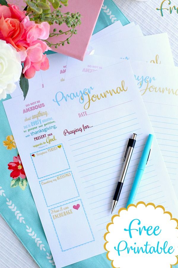 the free printable journal is next to a pen and flowers on a blue table cloth