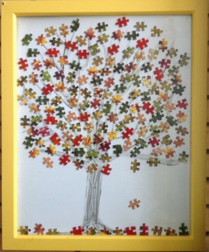 a colorful puzzle tree is shown in a yellow frame on the wall above it are several pieces of jigsaw