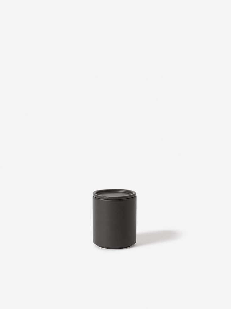 a black cup sitting on top of a white surface