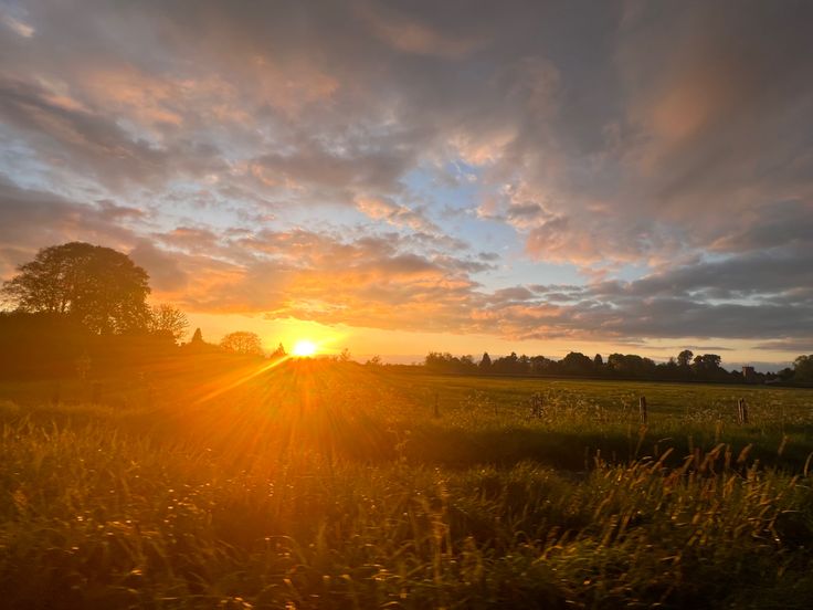 the sun is setting over an open field