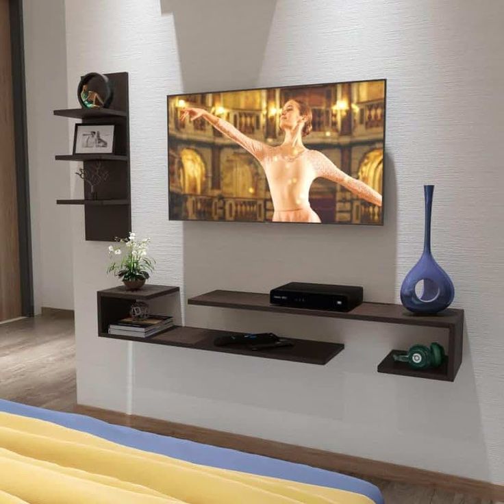 a flat screen tv mounted to the side of a wall next to a blue vase