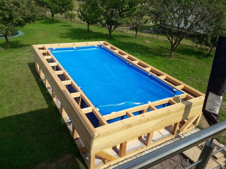 an above ground pool is being built in the yard with wood framing and blue tarp