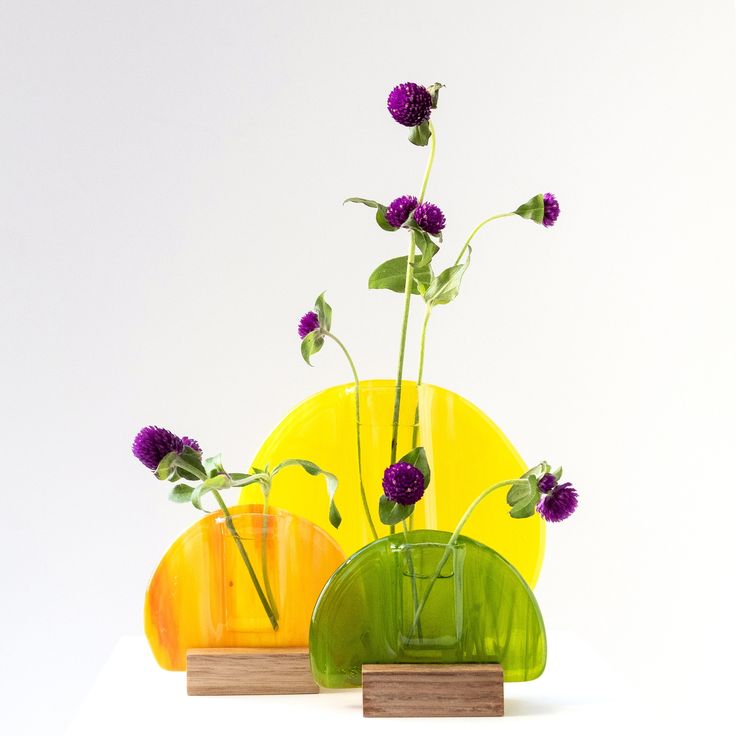 three vases with flowers in them sitting on top of each other, one yellow and the other green