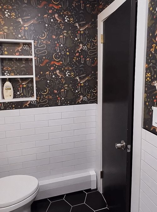 a bathroom with black and white wallpaper has a toilet in the corner next to it