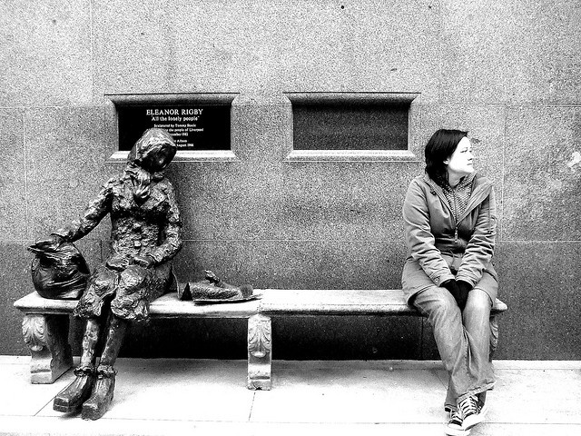 a woman sitting on a bench next to a statue