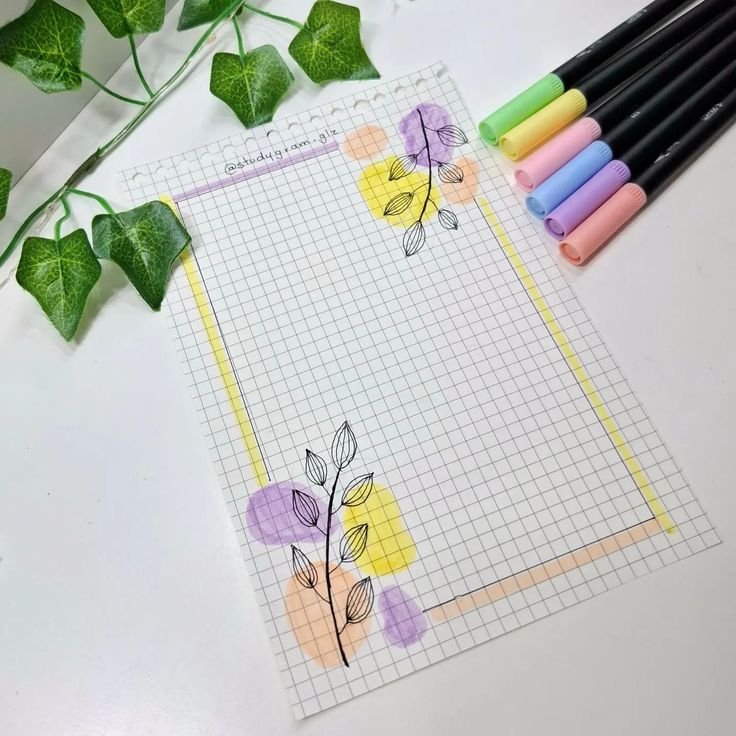 some crayons are laying on top of a piece of paper with flowers drawn on it