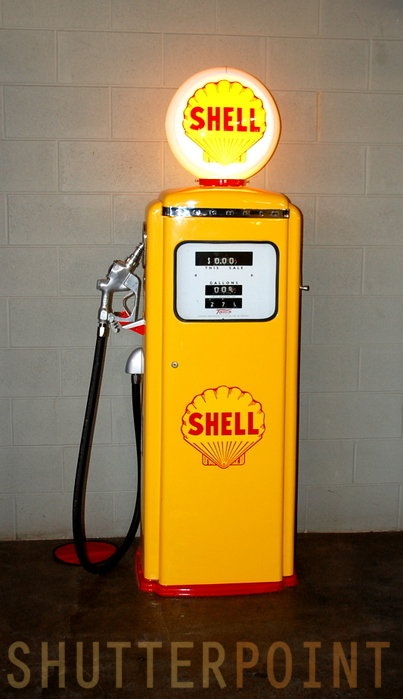 a yellow shell gas pump sitting on top of a wooden table