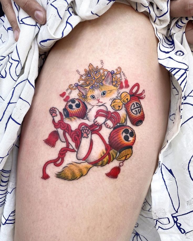 a woman's thigh with a tattoo on it that has a cat and other items