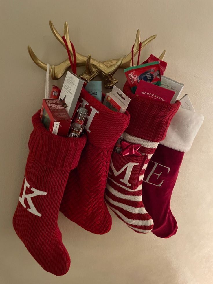 three christmas stockings hanging on the wall with reindeer antlers and other holiday items in them