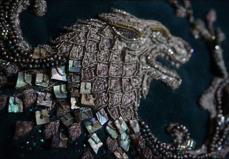 an intricately designed piece of jewelry is displayed on a black cloth with beads and stones