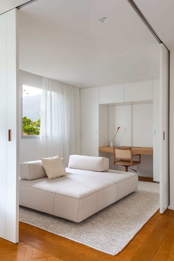 a large white couch sitting in the middle of a living room next to a window