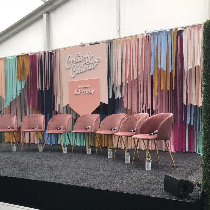 several pink chairs sitting on top of a carpeted floor next to a wall covered in curtains