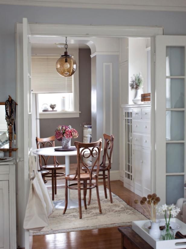 a dining room table and chairs in front of a white cabinet with glass doors leading to the kitchen